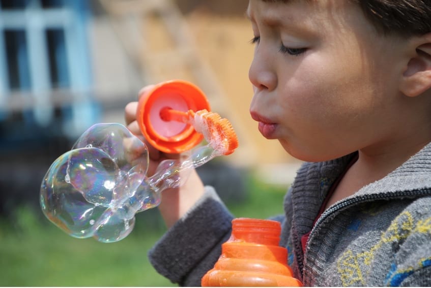 Child inflating the soap bubbles at summer outside