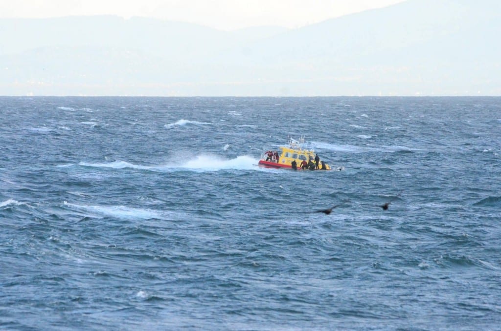 Approaching the over turned vessel and using a heaving line to get them off safely. Seas too heavy to come alongside. Image: RCM-SAR - Station 37 Sooke 